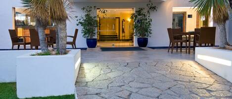 A reception area with a stone floor, potted plants, and wicker furniture.