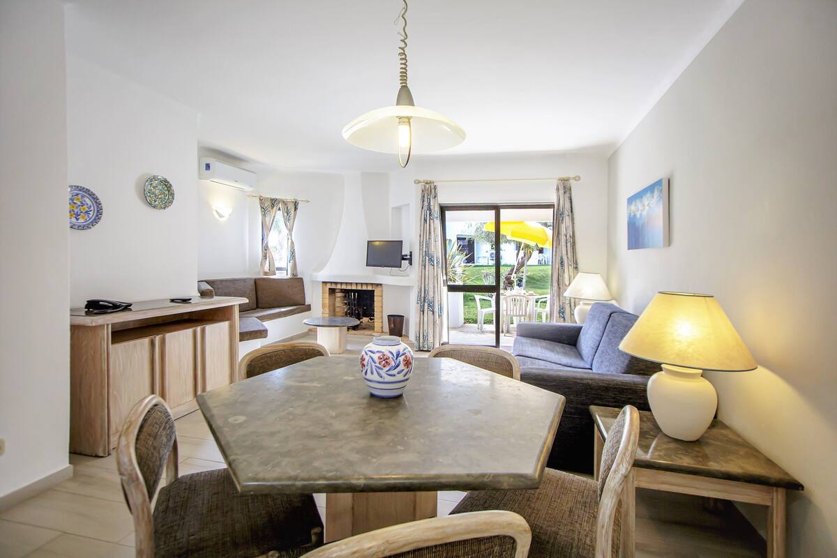 A modern living room with a dining table, chairs, a sofa, and a TV.