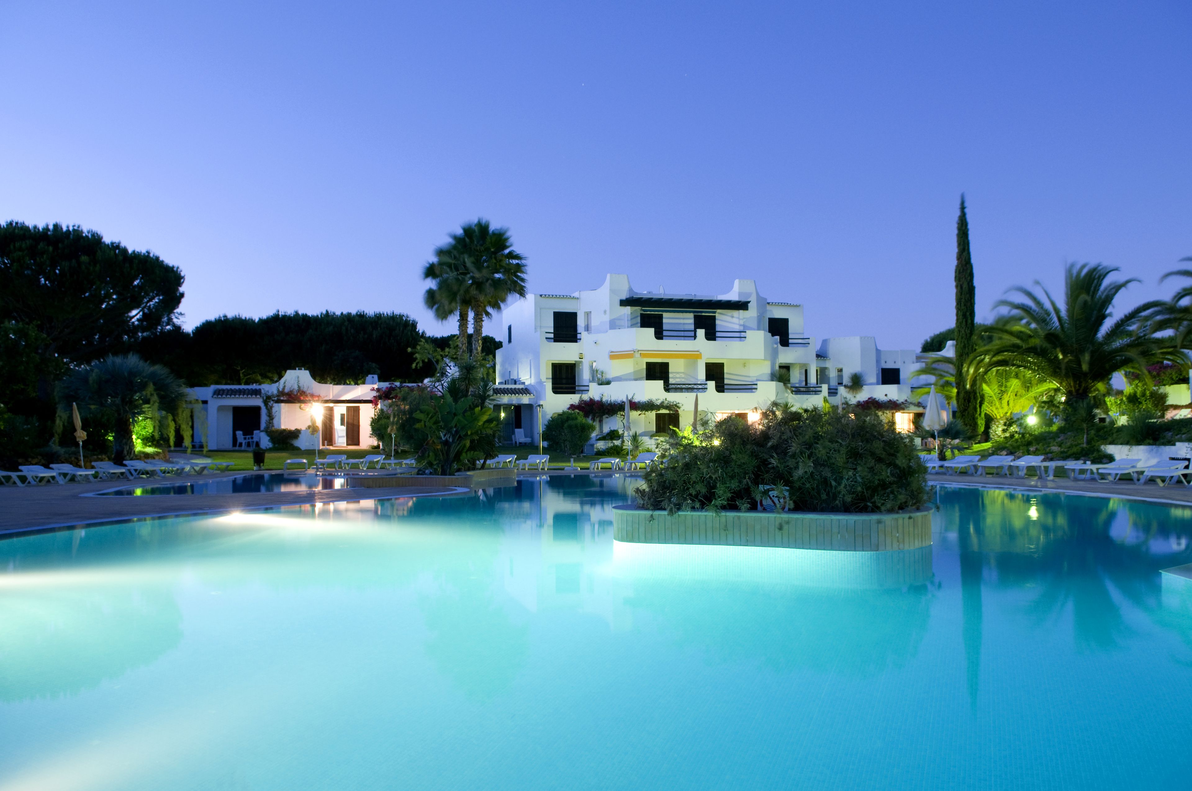 A swimming pool with lounge chairs and a building in the background.