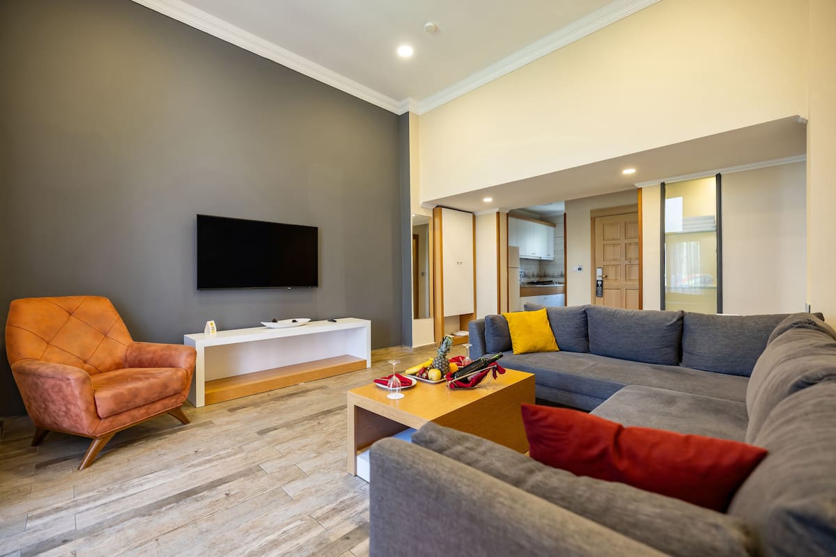 A modern living room with a grey sofa, a wooden coffee table, and a leather armchair.