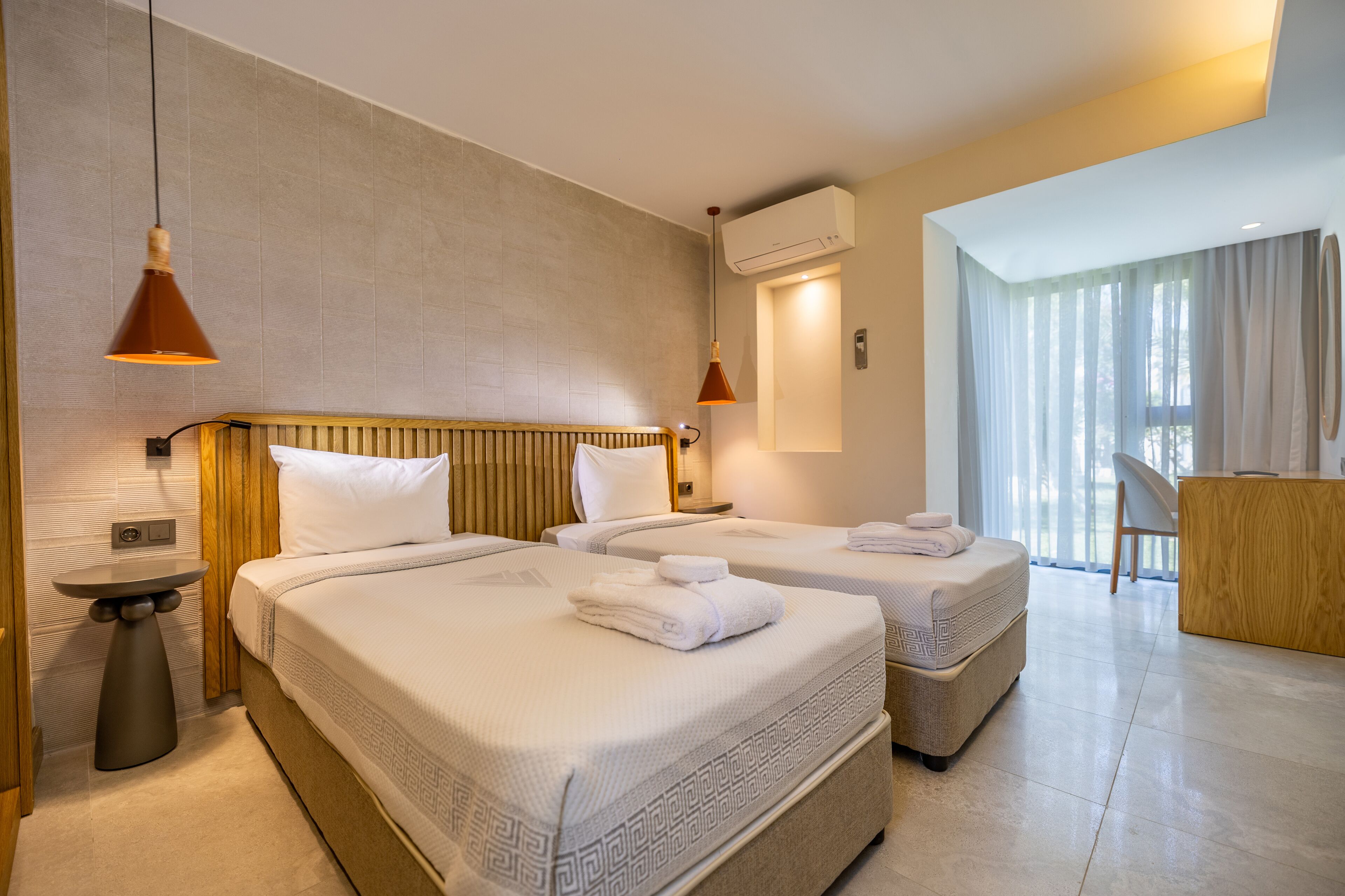 Habitación de hotel con dos camas, un escritorio y una silla.