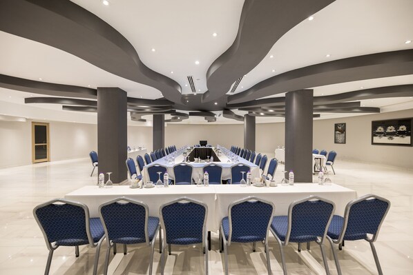 A conference room with a long table, blue chairs, and a modern ceiling design.