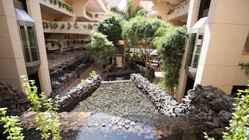 Stunning atrium with a central water feature surrounded by lush greenery and stone walls.