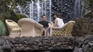 Una pareja sentada en una mesa con una cascada al fondo.