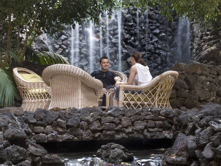 Una pareja sentada en una mesa con una cascada al fondo.