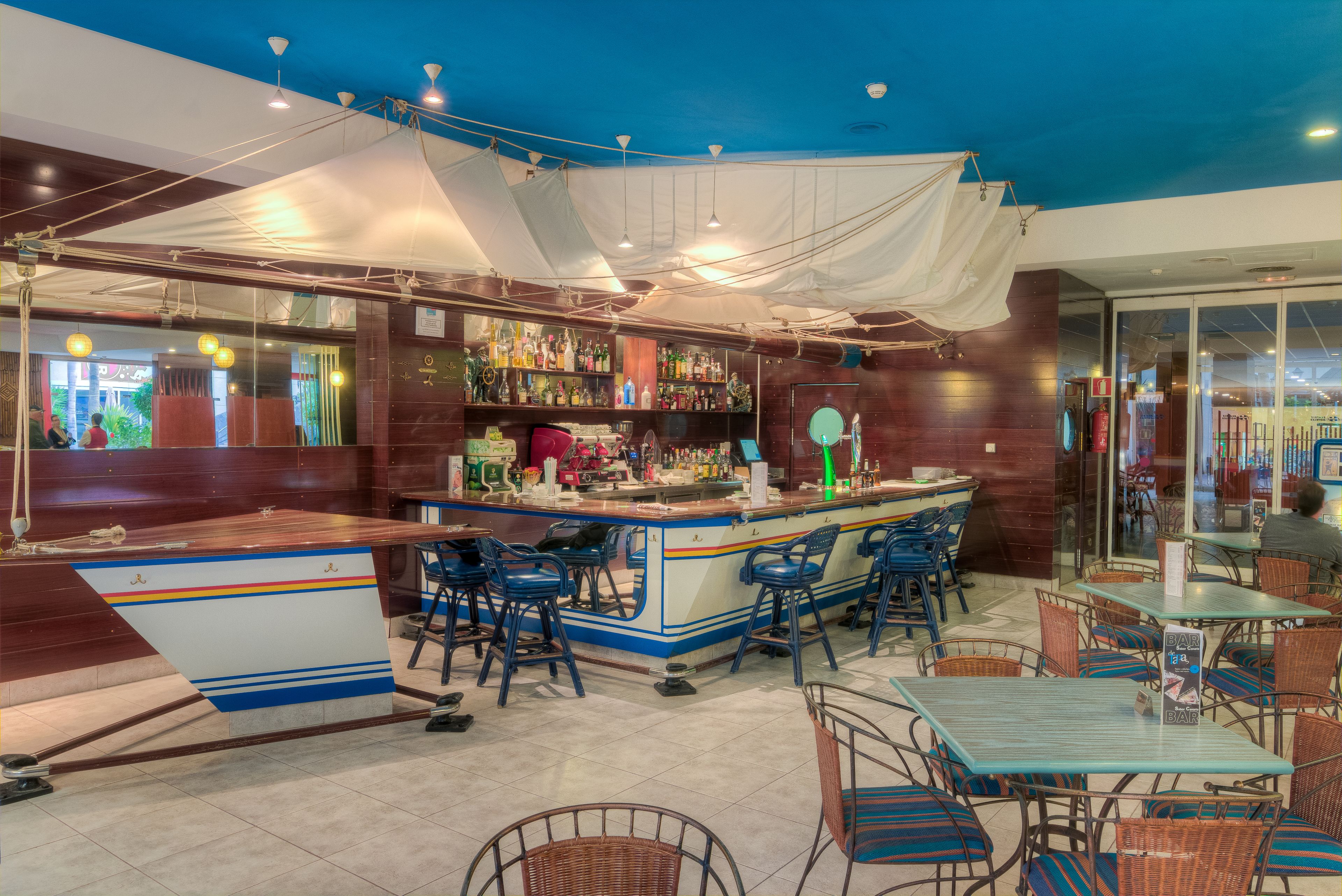 A bar area with a counter, stools, and tables.