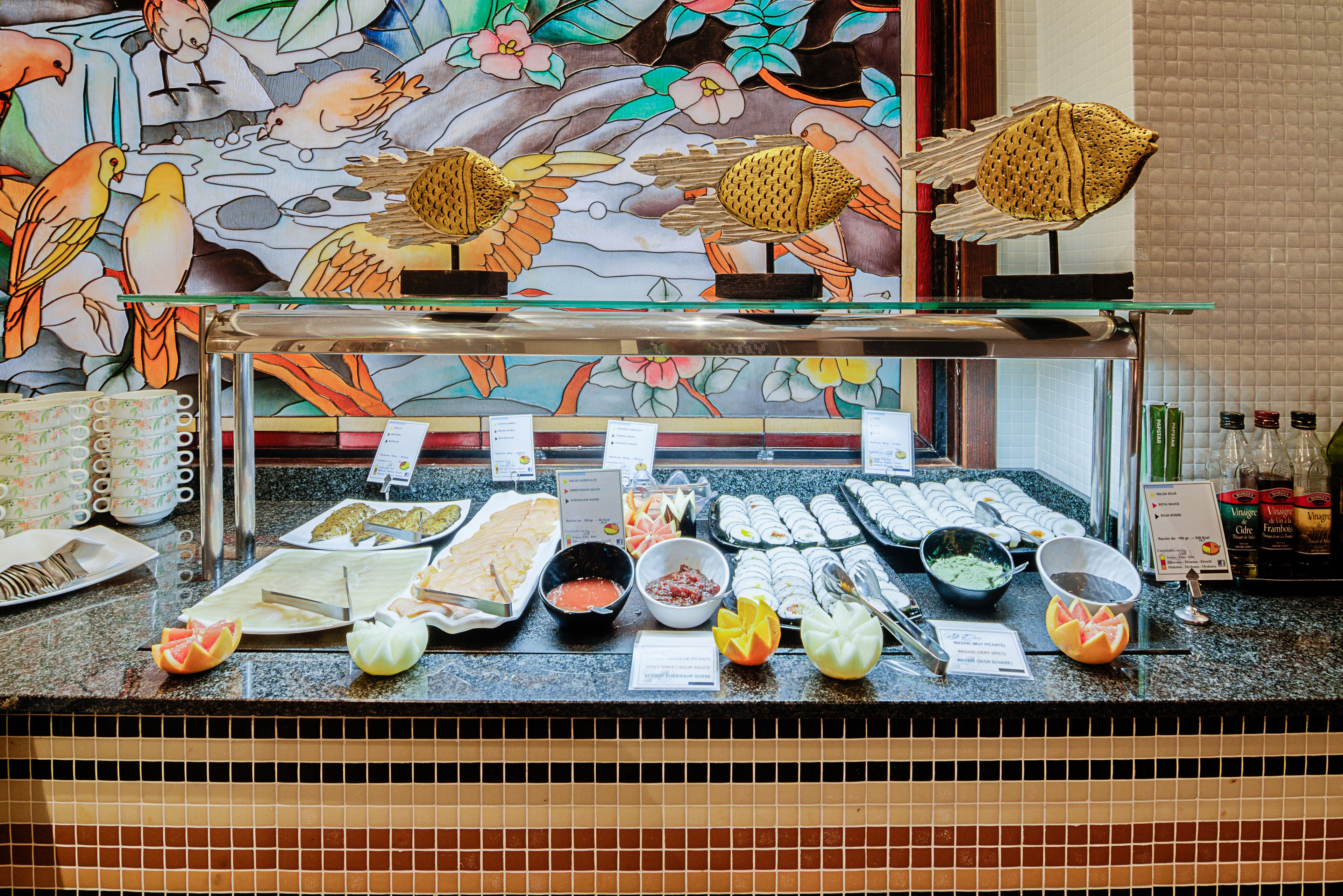 Un bufé con diferentes opciones de comida y una pared decorativa con aves.