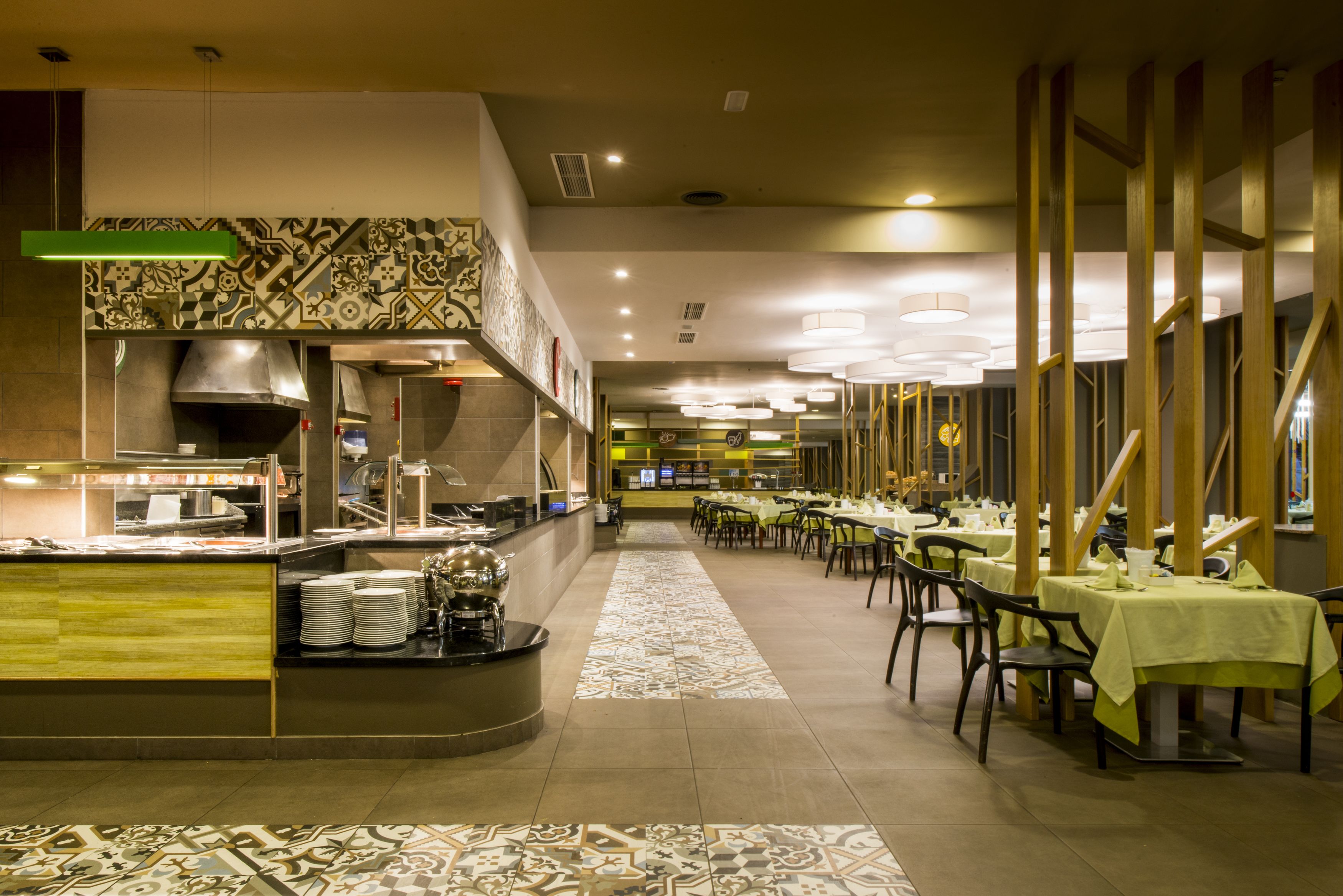 Un restaurante con zona de bufé, varias mesas para comer y piso estampado.
