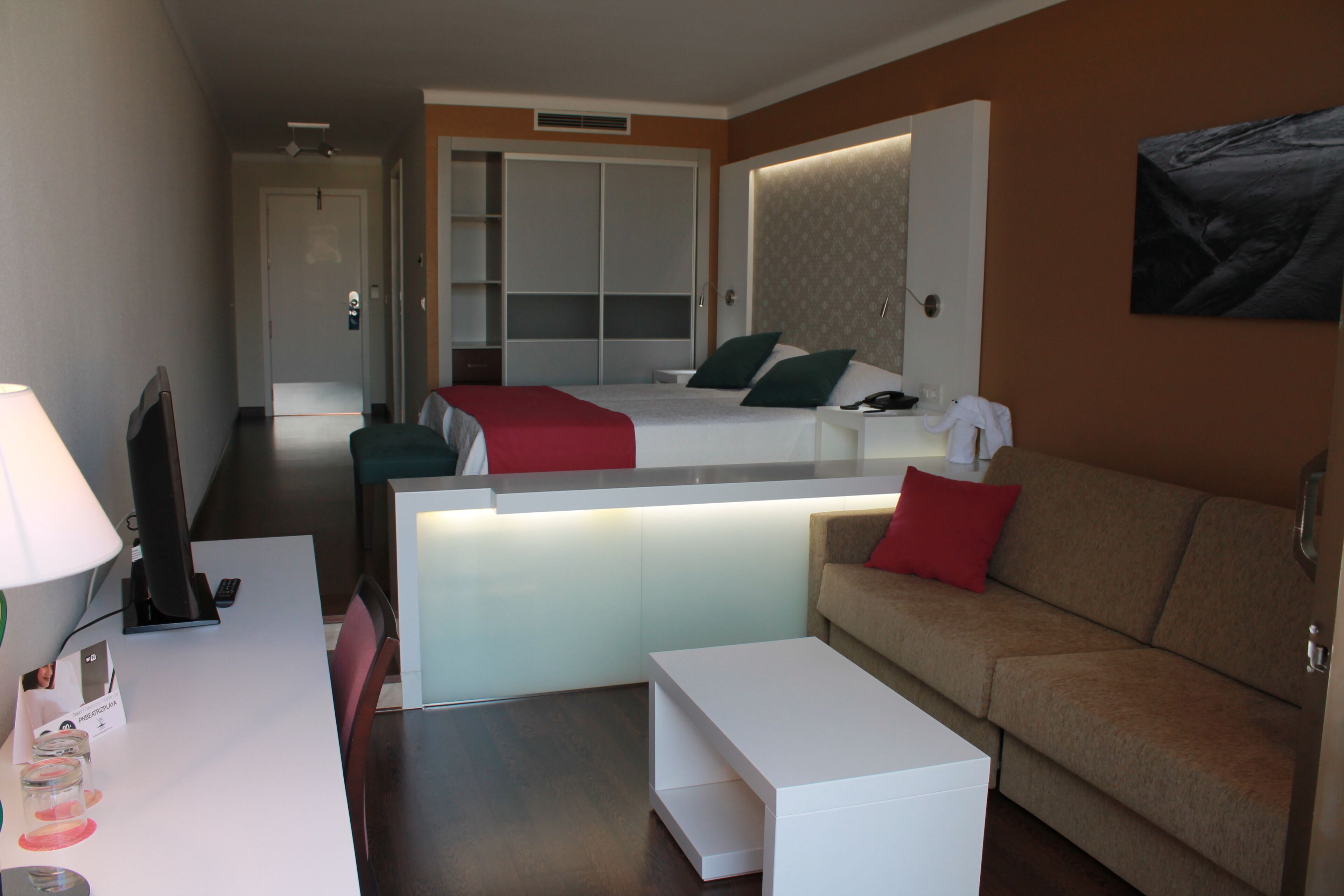 A hotel room with a bed, a desk, a couch, and a bathroom.