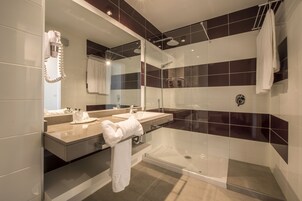 A modern bathroom with a glass-enclosed shower, a vanity with a mirror, and a towel rack.