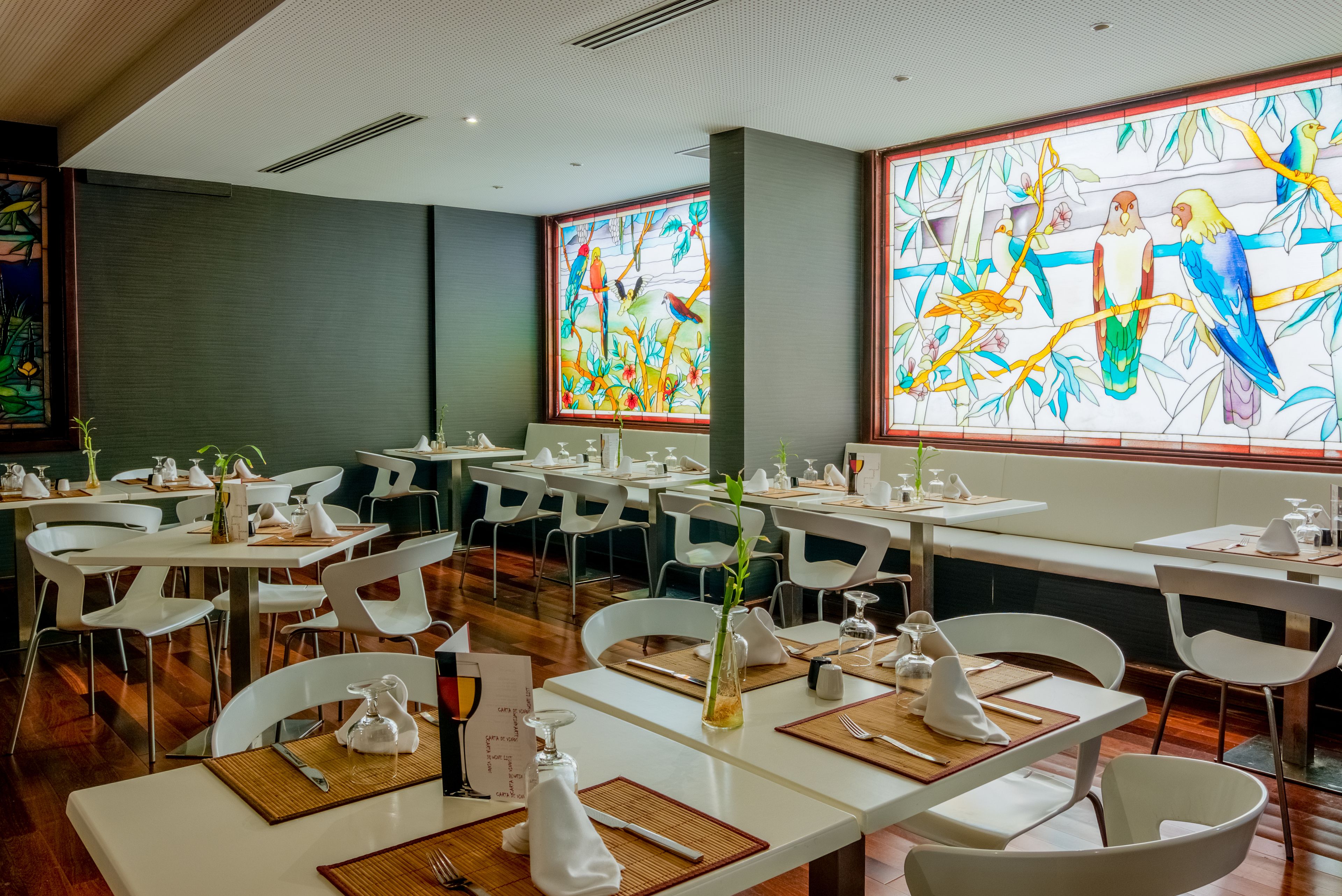 A restaurant with white tables and chairs, stained glass windows, and a modern interior design.