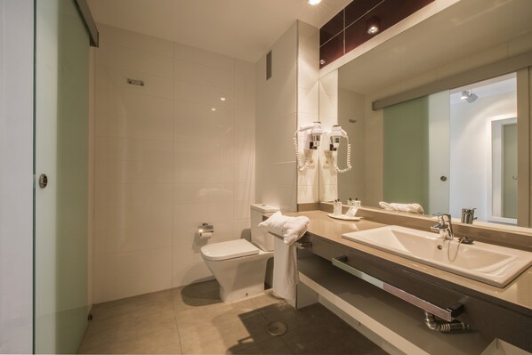 Un baño moderno con cabina de ducha de vidrio, inodoro, lavabo con espejo y toallero.