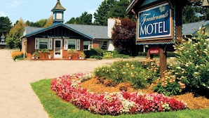 Un motel con un letrero llamativo, una pequeña estructura parecida a una torre y una arribera bien cuidada.