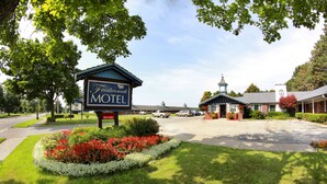 Motel Frank Kernmuth con un cartel, rodeado de césped cuidado y parterres de flores.