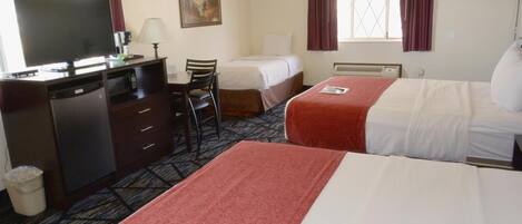 A hotel room with two beds, a desk with a television, a chair, and a waste bin.