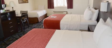 Una habitación de hotel con dos camas, un escritorio con silla, un aparador y una ventana con cortinas.