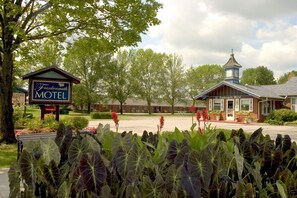 Ein Motel mit einem auffälligen Schild, einem kleinen Turm und einem gepflegten Garten.