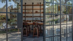 A room with a glass wall, wooden shelves with various items, and a dining area with chairs and a table. - 4Reasons Hotel And Bistro | 12+ (Bodrum)