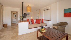 A modern living room with a wooden coffee table, a sofa with red cushions, a wicker chair, and a hanging light fixture. - 4Reasons Hotel And Bistro | 12+ (Bodrum)