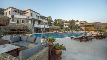 A poolside area with lounge chairs, a sofa, and potted plants.