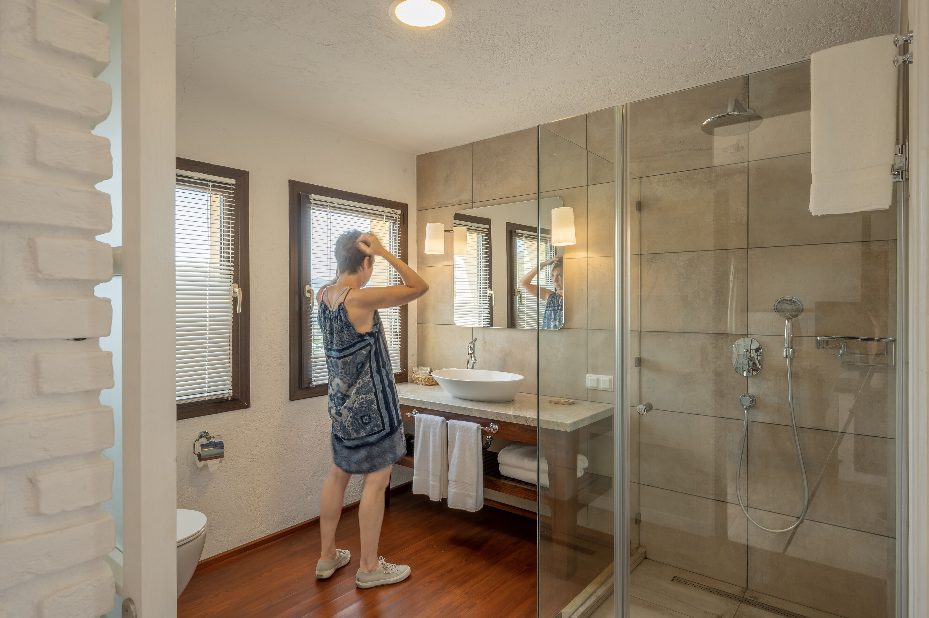 A bathroom with a glass shower enclosure, a sink with a mirror, and a towel rack.