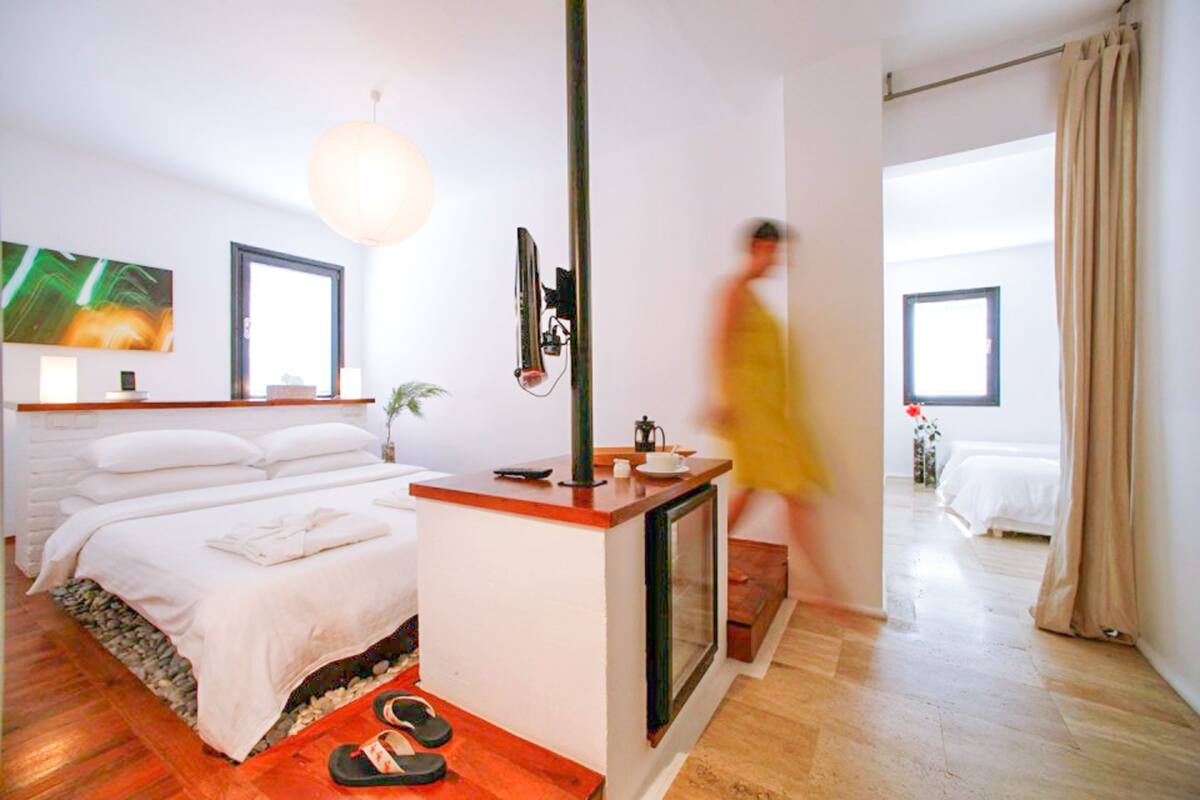 Quarto de hotel moderno com uma cama, uma mesa de escritório, uma televisão e uma janela grande.