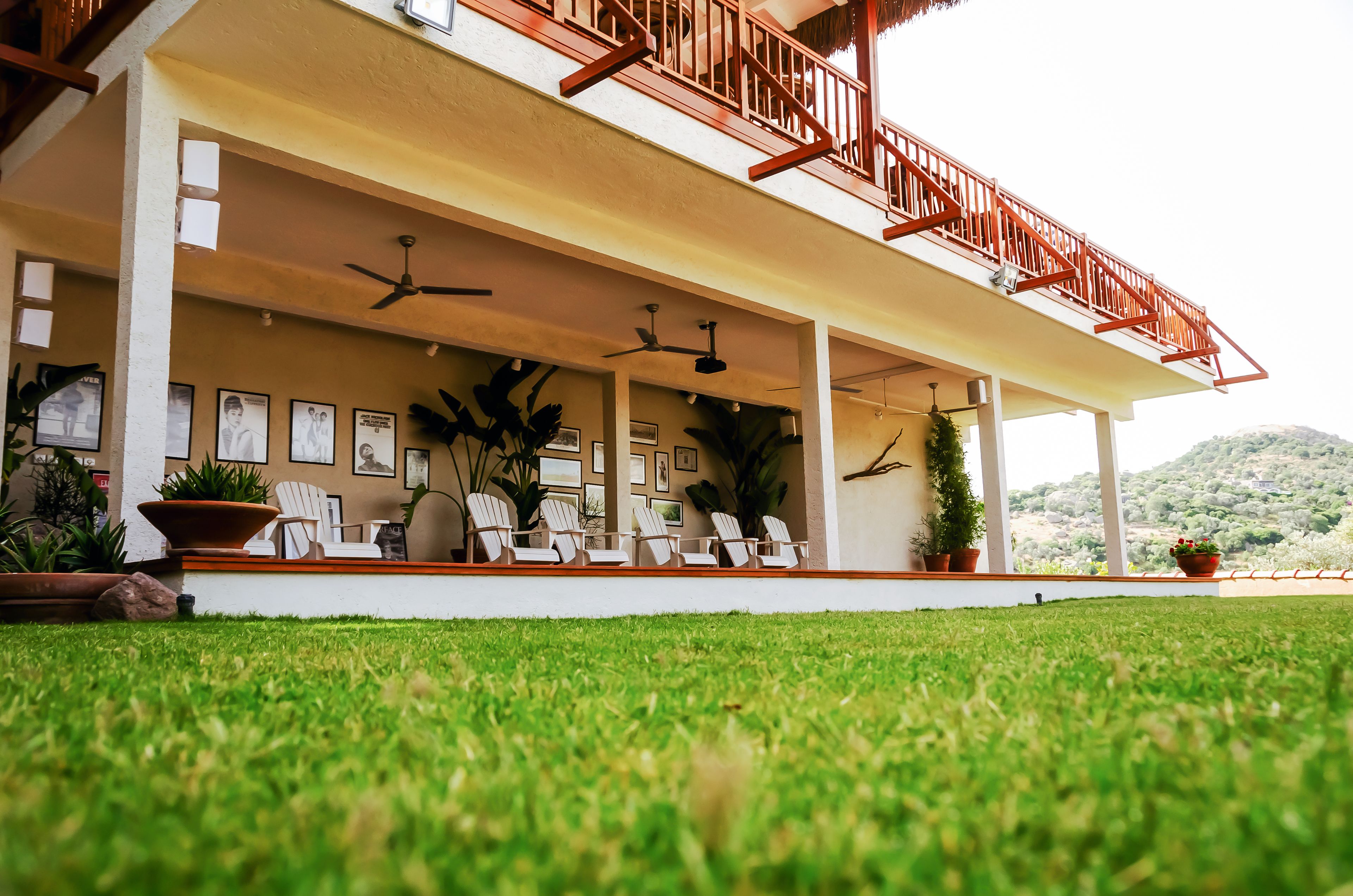 A covered outdoor area with ceiling fans, white chairs, and potted plants.