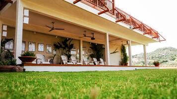 A covered outdoor area with ceiling fans, white chairs, and potted plants.
