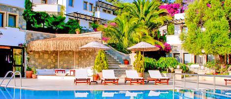 Alberca al aire libre, sombrillas en la alberca y camastros