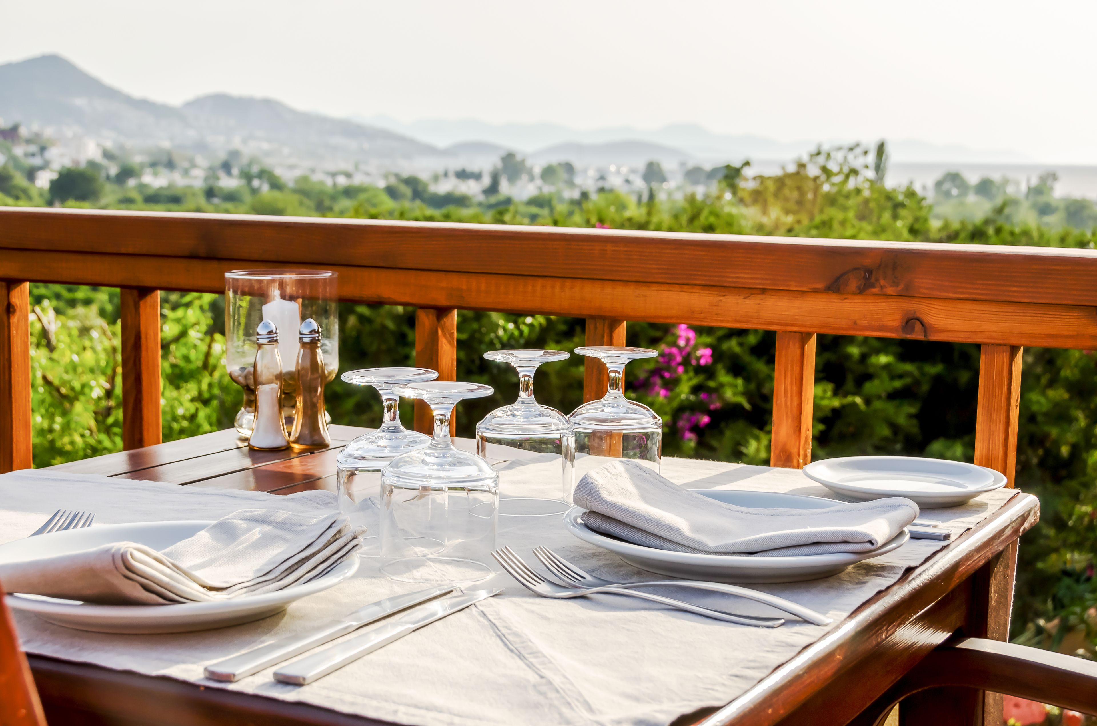 A table set for dining with a scenic view of mountains and greenery in the background.