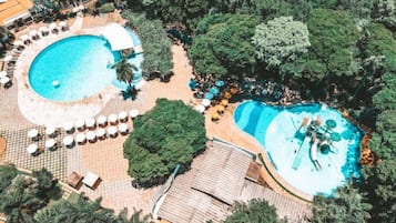 Una piscina techada, una piscina al aire libre, sombrillas