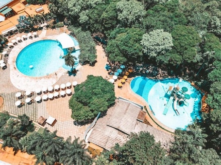 Una piscina techada, una piscina al aire libre, sombrillas
