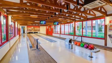 A bowling alley with wooden beams, a polished floor, and a row of colorful bowling balls.