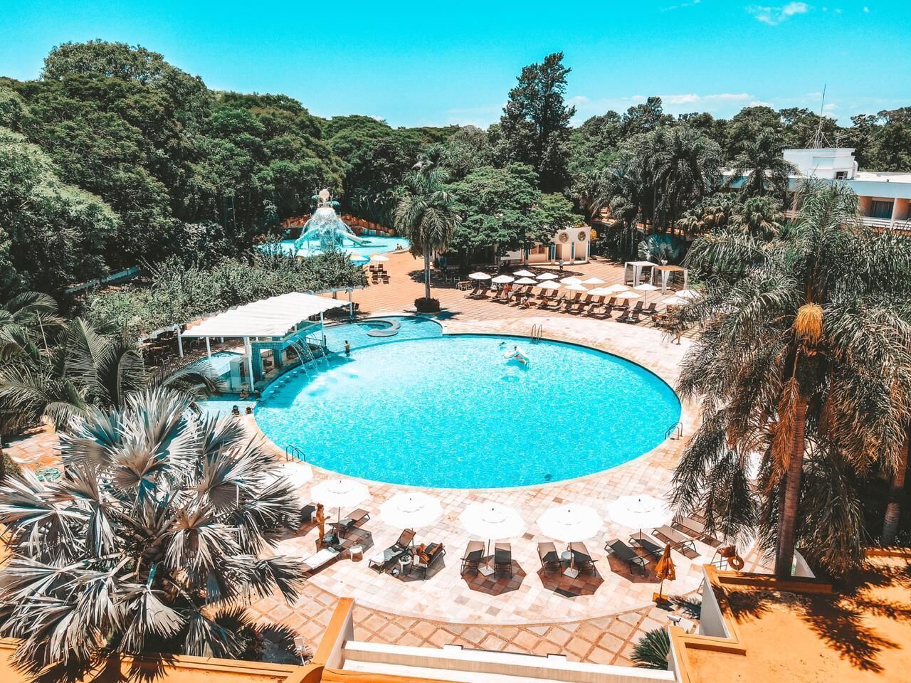 Una piscina techada, una piscina al aire libre, sombrillas