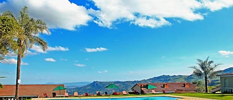 Una piscina al aire libre, sombrillas, sillones reclinables de piscina