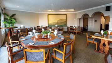 A conference room with round tables, chairs, and a large painting on the wall.