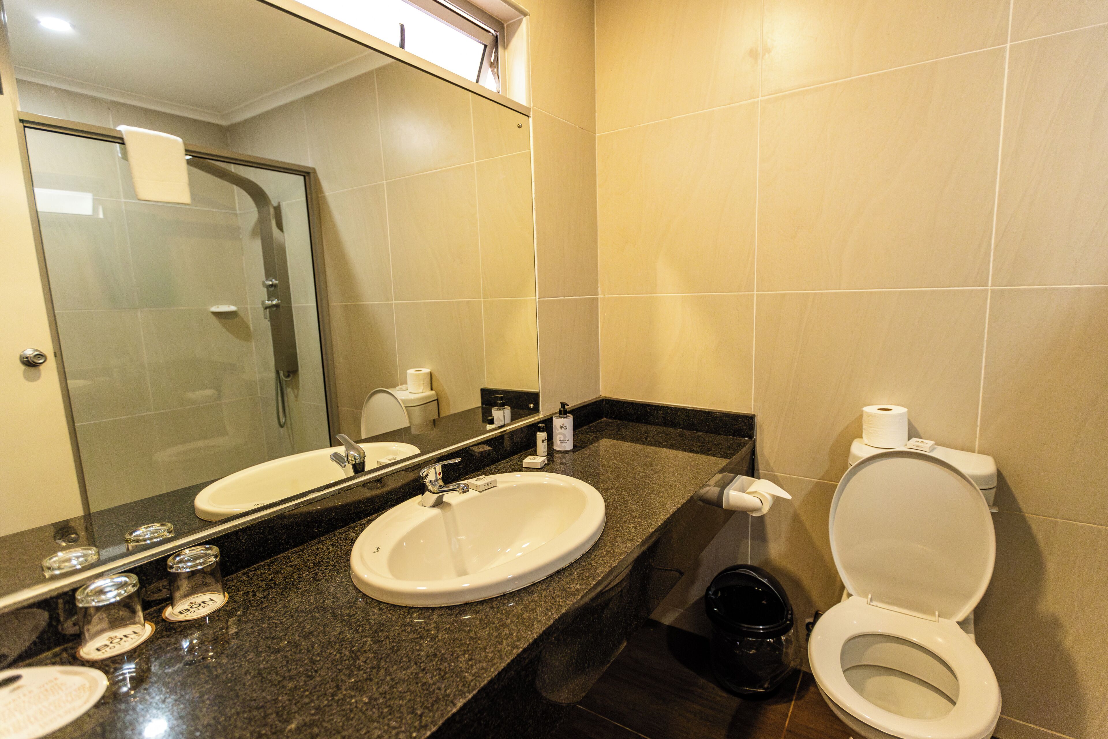 A bathroom with a sink, mirror, toilet, and shower.
