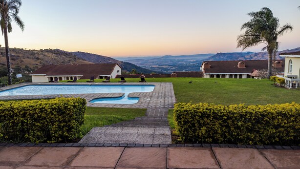 A pool with two sections, a lawn, and a view of distant hills. -  Mountain View International Hotel (Mbabane)
