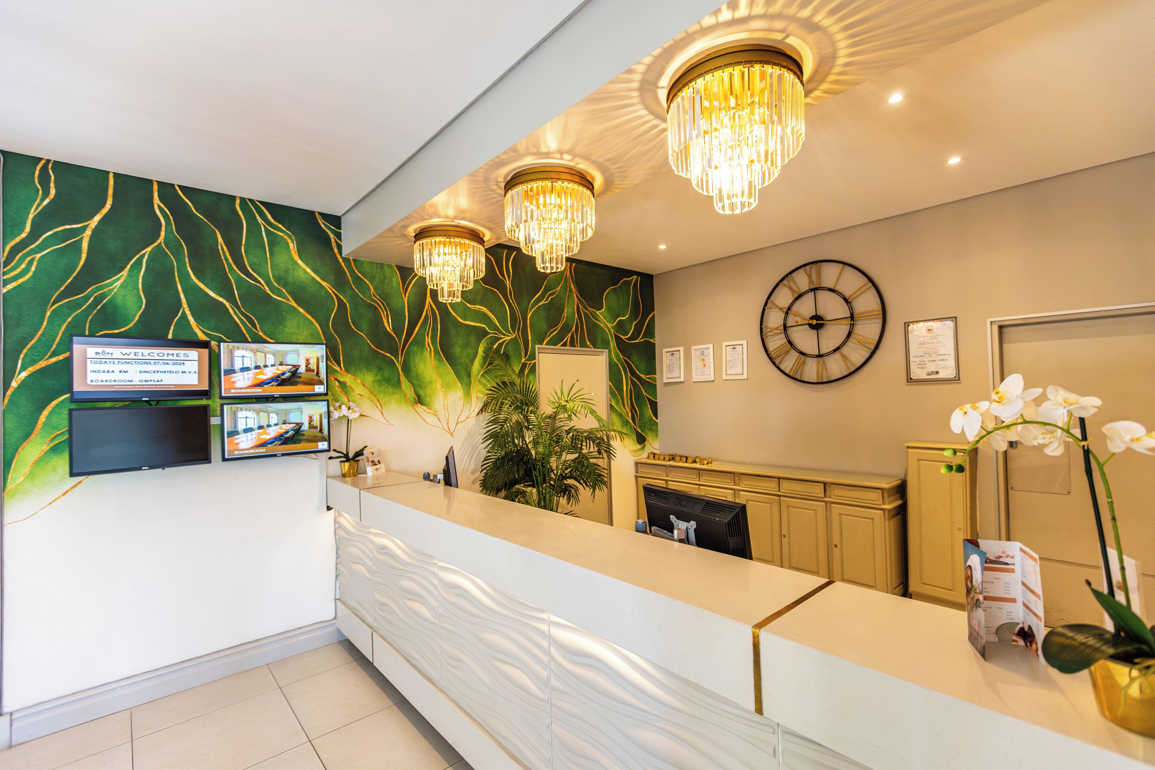 A reception area with a modern design, including a reception desk, wall-mounted TV, and decorative lighting.