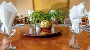 Una mesa de comedor con una planta en el centro, dos copas de vino y un mantel individual.