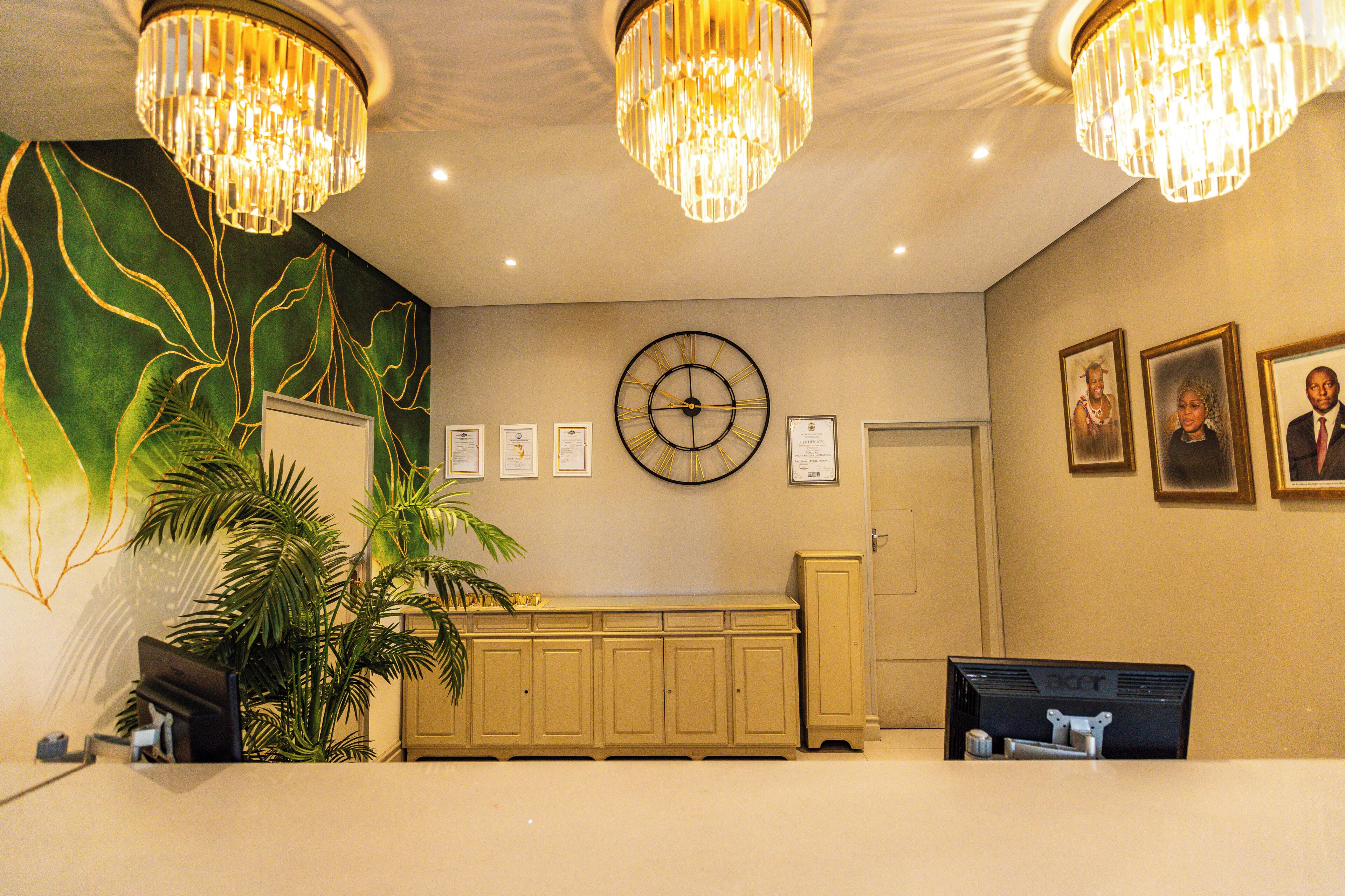 A reception area with a clock, framed certificates, and a plant.