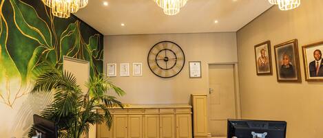 A reception area with a clock, framed certificates, and a plant.