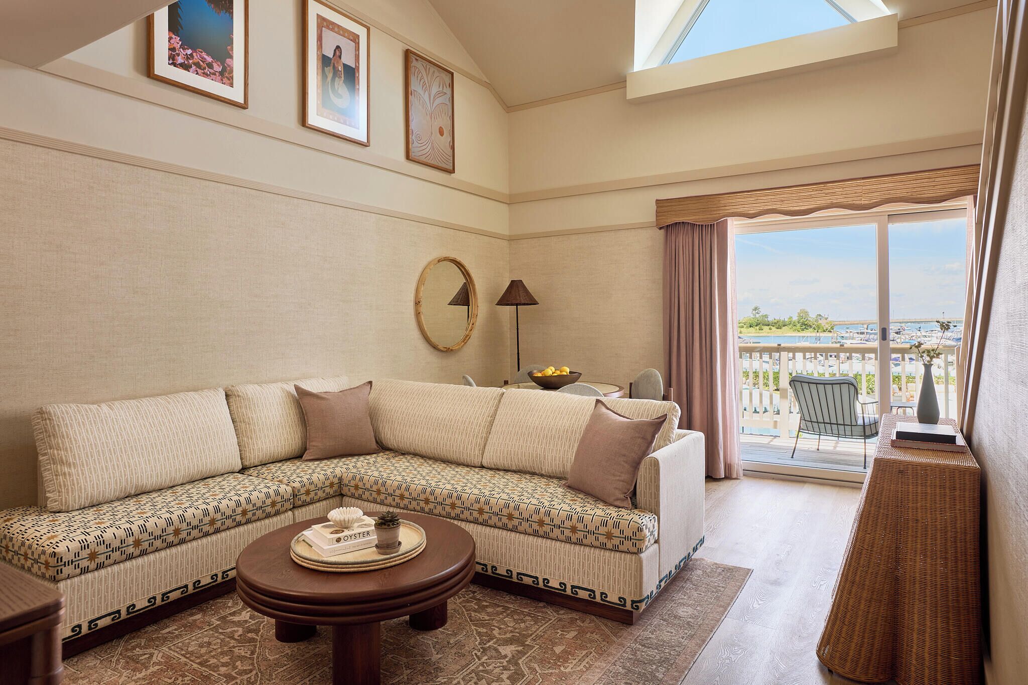 A living room with a sectional sofa, a round coffee table, a lamp, and a view of the outdoors.
