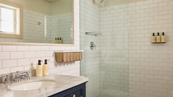 Un baño con un espejo grande, dos lavamanos, un inodoro y una ducha.