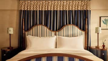 A bed with a wooden headboard, two bedside tables with lamps, and a patterned curtain.