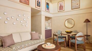 A living room with a sofa, chairs, a round table with a tray, a mirror, and wall decor.