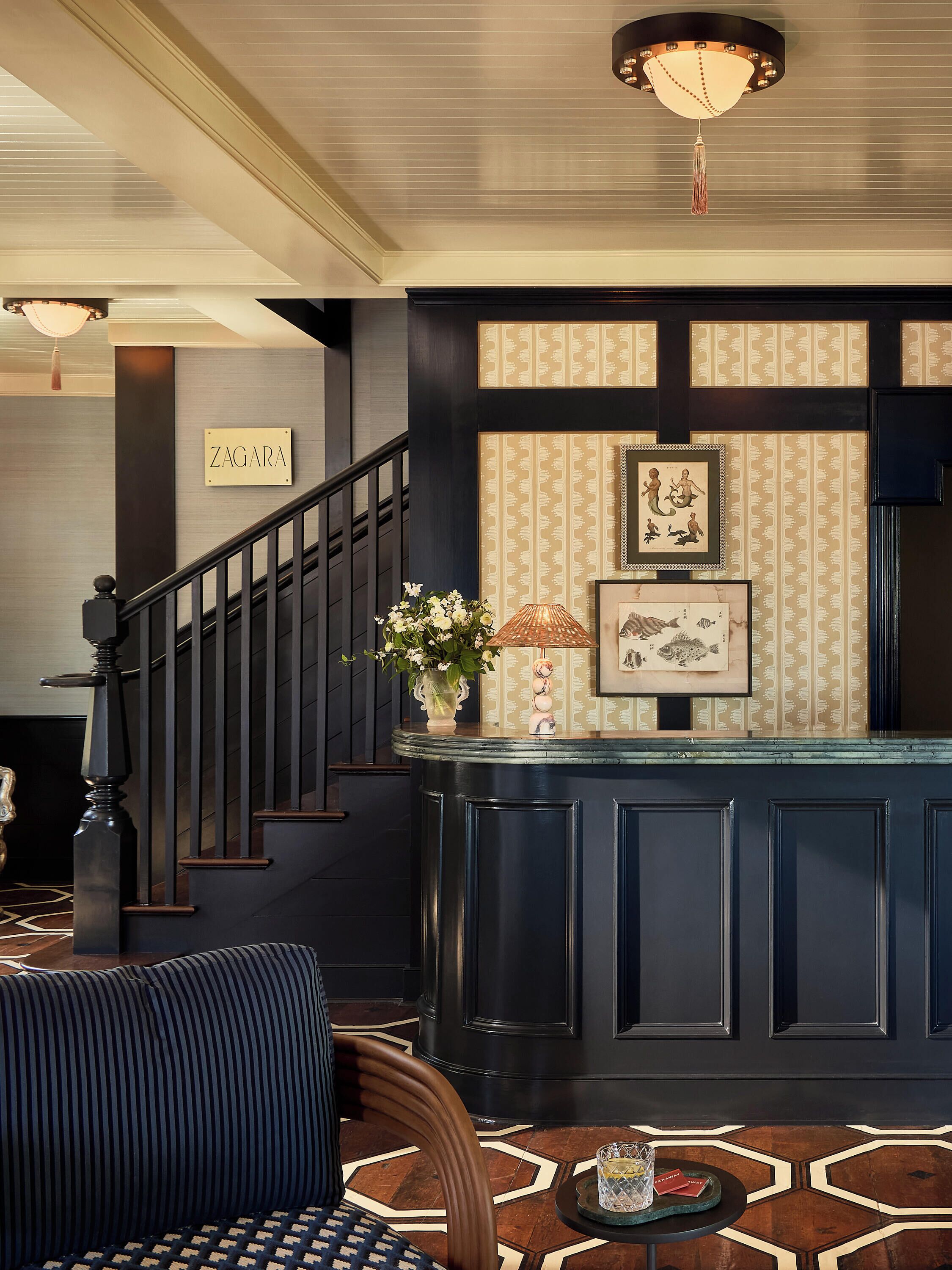 A lobby with a staircase, a reception desk, and a wall with framed artwork.