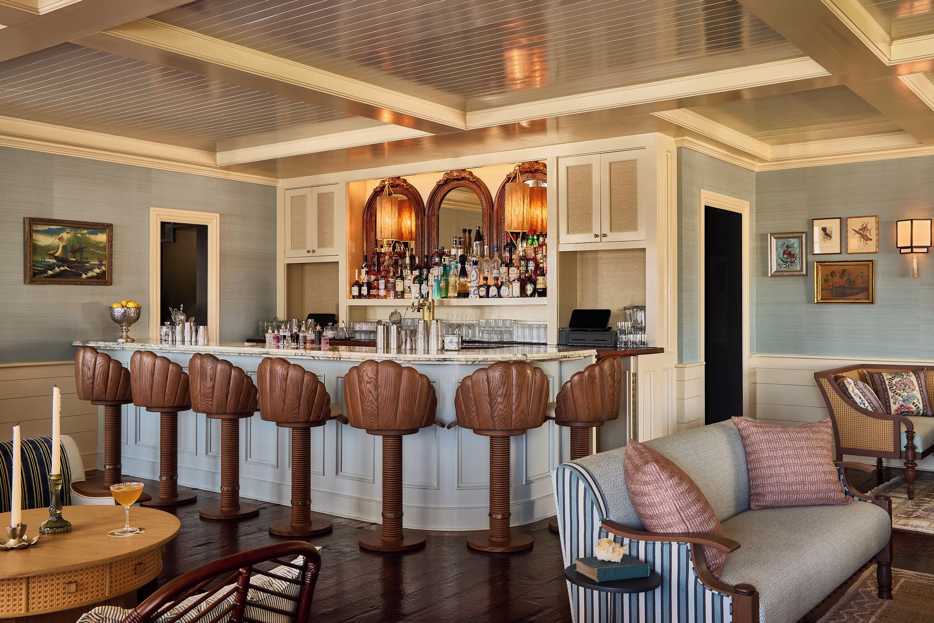 A bar area with stools, a counter, and a seating area with a sofa and chairs.