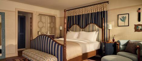 A four-poster bed with a canopy, a bench, a daybed, and a small table with a lamp.