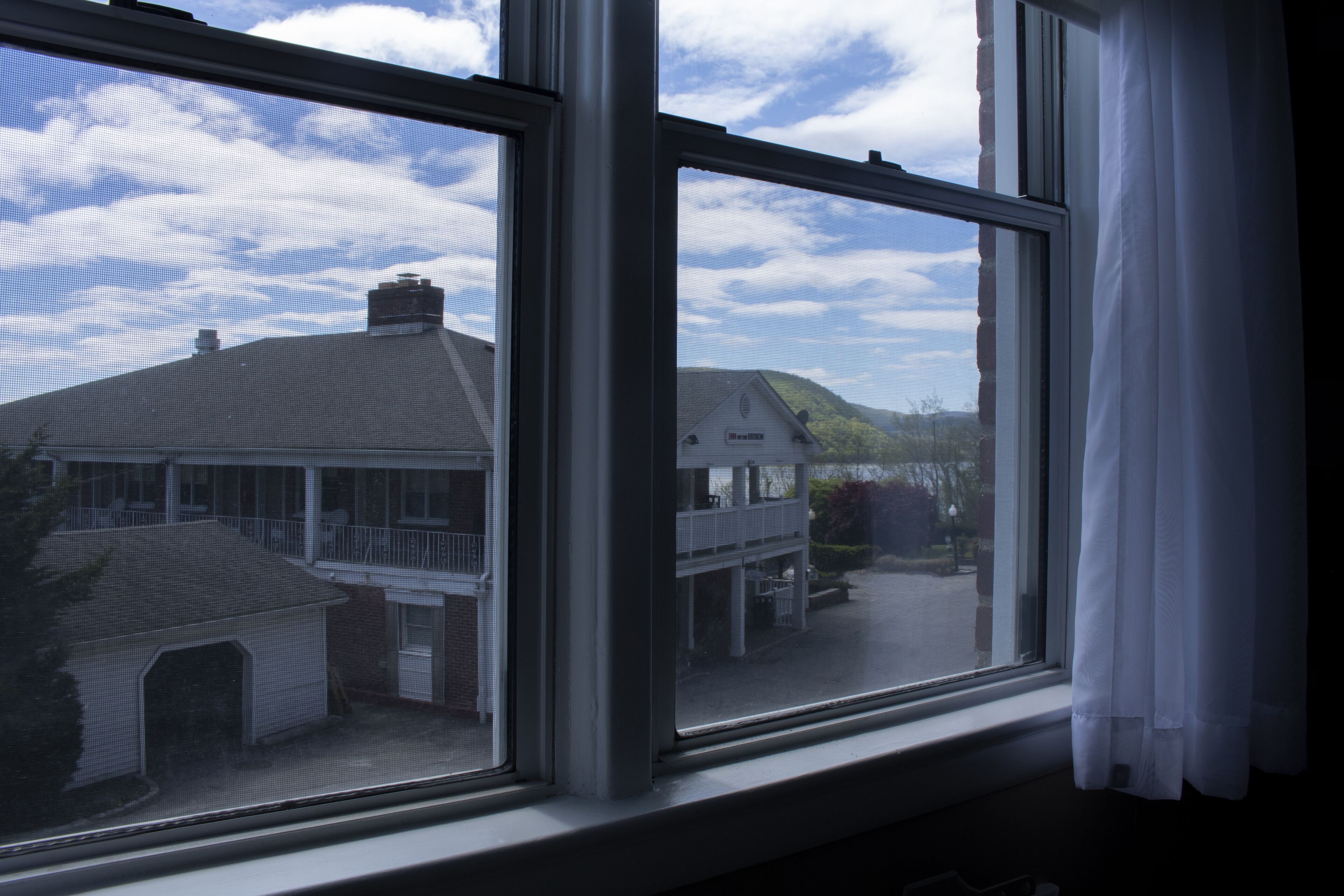 A view through a window with a view of a building with a balcony and a covered area.